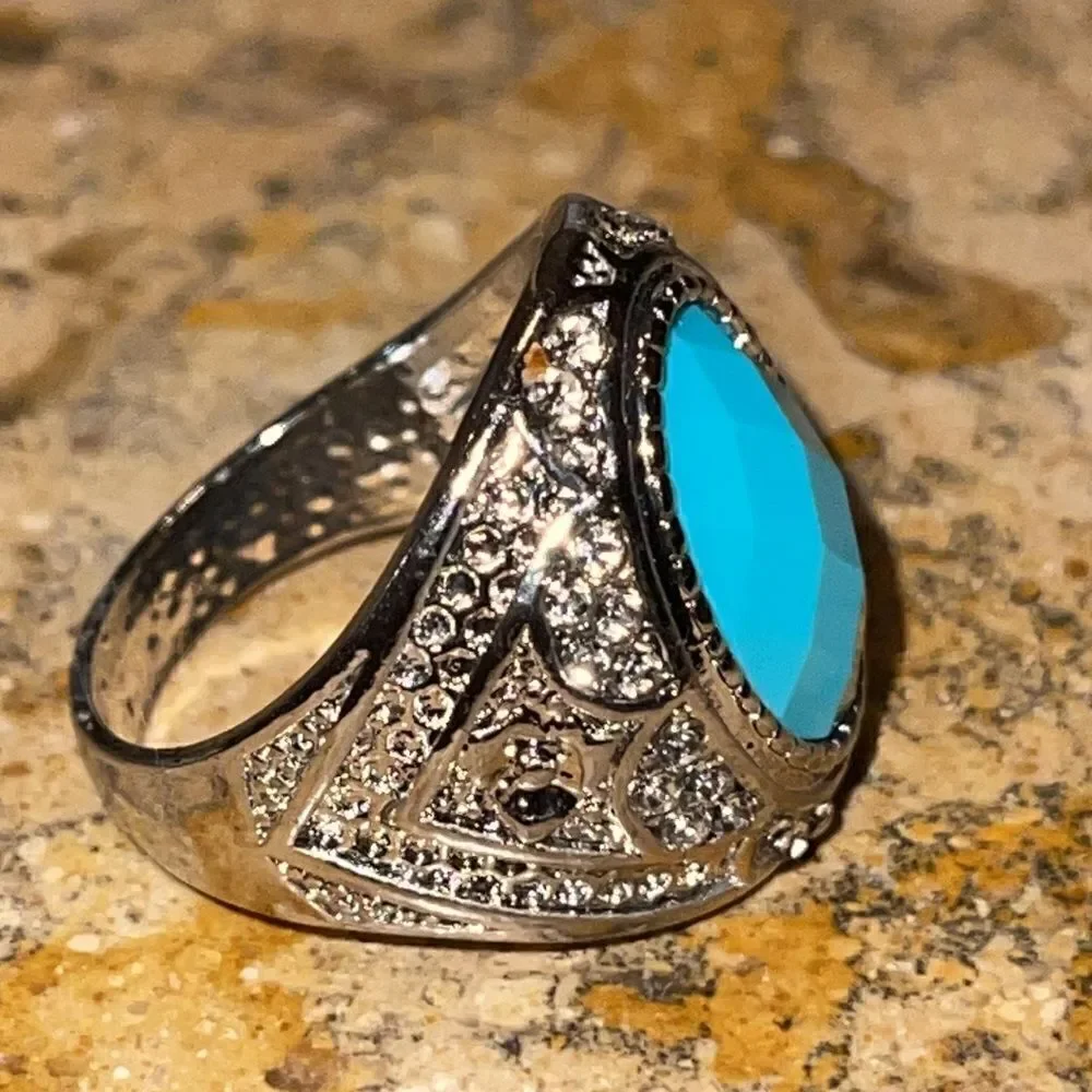 Costume jewelry silver tone ring with turquoise color acrylic center stone.